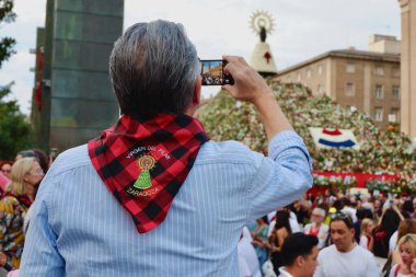 Zaragoza, Aragon, İspanya - 13 Ekim 2023: Yaşlı adam Virgen del Pilar bayram gününde çiçek mantosunun mobil fotoğrafını çekiyor. İspanya ulusal günü, Zaragoza 'da Amerika' nın keşfini kutlamak için her yıl büyük bir olay düzenlendi..