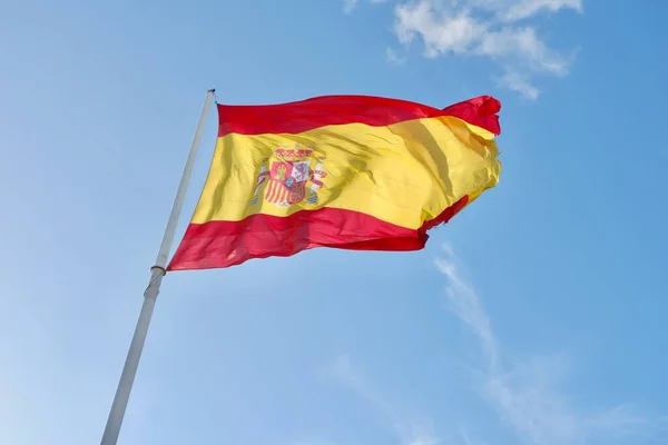 Flag of Spain waving on the strong wind against blue sky in Madrid, Spain.