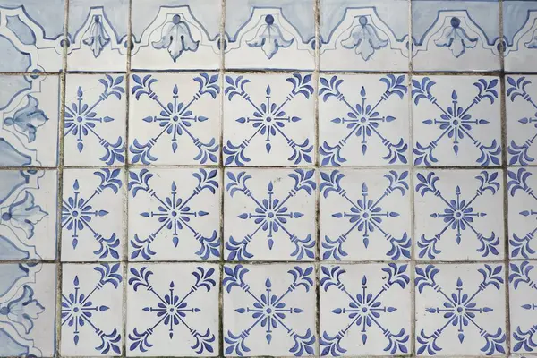 Antique old-fashioned tiles of faded blue colour on the weathered facade in Lisbon, Portugal