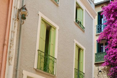 Fransa 'nın küçük bir kasabasında şehir merkezinde dar bir sokakta pastel renklerin kepenkli pencereleriyle klasik Fransız cephelerinin üst görüntüsü.