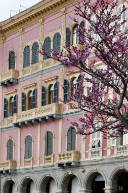 İtalya 'nın Sardunya, İtalya' da kırmızı, pembe ve bej renklerin mimari geleneğinde yapılmış zarif zengin cephesi..