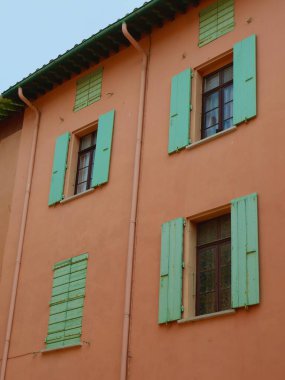 Fransa 'da canlı sıcak renklerin kırsal Fransız cephesinde eski moda açık ve kapalı panjurları olan Vintage pencereler.