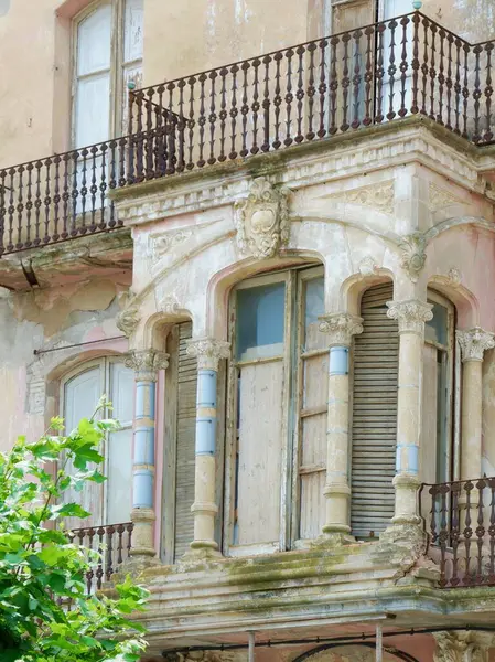 Çok güzel detaylandırılmış bir balkon, karmaşık tasarım unsurları ve bir tarih anlayışı barındıran eski bir binanın üzerinde yer almaktadır. Yıpranmış ahşap ve solmuş boya cazibesini gösterir.