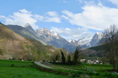 Nefes kesen manzara karla kaplı zirveler yemyeşil tarlaların üzerinde yükseliyor. Kabarık bulutlar gökyüzünde sürükleniyor, baharda sakin bir atmosfer yaratıyor..