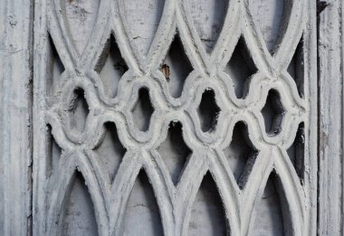 Eşsiz gri mimari detay, yıpranmış ahşaba oyulmuş iç içe geçmiş desenler, işçilik ve tarihsel önemi vurgulayan süslü bir tasarım sergiliyor..