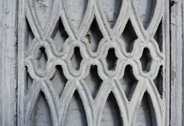 Eşsiz gri mimari detay, yıpranmış ahşaba oyulmuş iç içe geçmiş desenler, işçilik ve tarihsel önemi vurgulayan süslü bir tasarım sergiliyor..