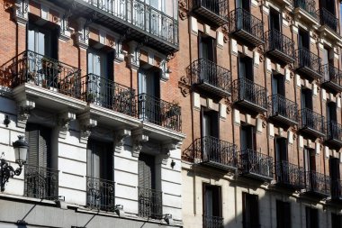 Yapı cephesinin iki farklı şekli aydınlık gündüz saatlerinde hareketli bir kentsel ortamda mimari çeşitliliği gösteriyor..