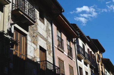 Benzersiz balkonları ve taş duvarları olan canlı yapılar sessiz bir cadde oluşturur. Güneş gölgeler saçar, bu güzel kasabanın büyüleyici atmosferini güçlendirir..