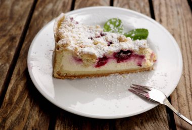 Kirazlı cheesecake, Almanya 'da bir ahşap masada açık bir tabakta yemeye hazır.