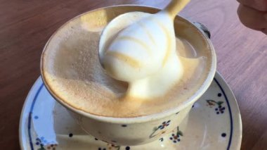 Ahşap arka planda bir fincan kahvenin içindeki köpüklü kahve.