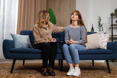 Genç kadın evde kadın psikologla konuşuyor.