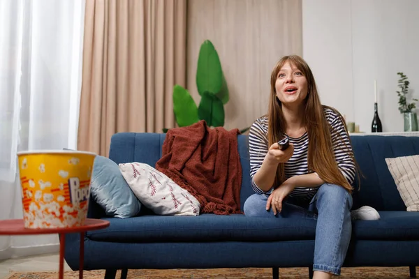 Neşeli Genç Bir Kadın Televizyon Seyrediyor Rahat Koltukta Oturuyor Elinde — Stok fotoğraf