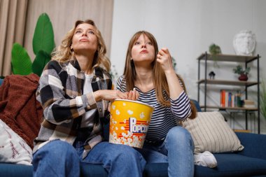 Farklı yaşlarda iki kadın heyecan verici bir film izler ve evdeki kanepede otururken patlamış mısır yer.