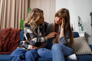 Bana sorunlarından bahset. Kanepede oturan orta yaşlı bir kadın genç kızını teselli ediyor.