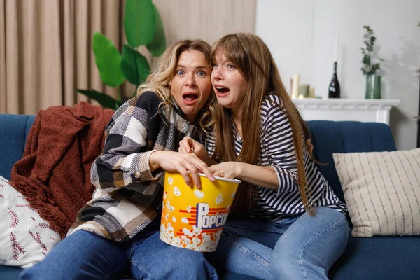 stock image Two scared women on sofa watching horror movie on TV at home