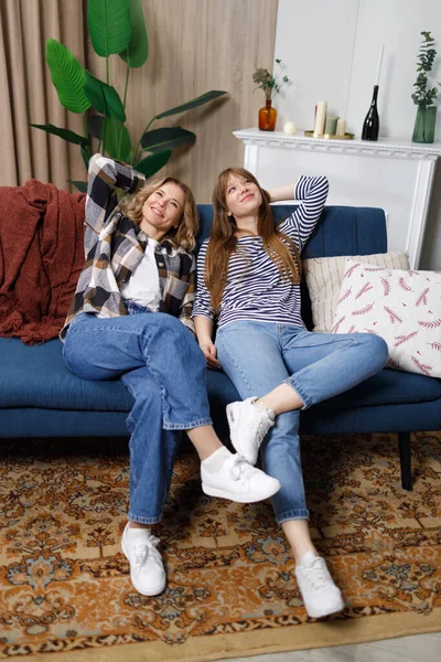 stock image Two female friends of different ages relax on couch hands over head