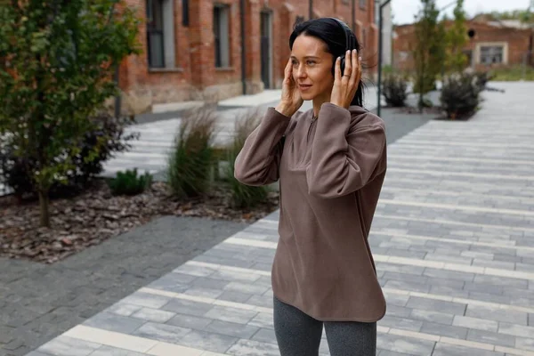 Kulaklıklı Kadın Caddenin Ortasında Dikilmiş Müzik Dinliyor Koşuya Hazırlanıyor — Stok fotoğraf