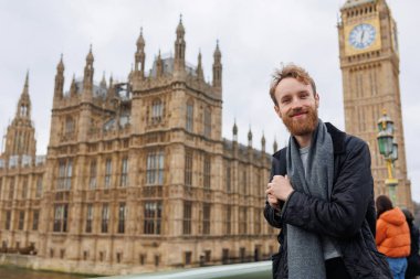 Londra 'da Big Ben' in arka planına karşı sırt çantalı sakallı bir erkek gezginin portresi.