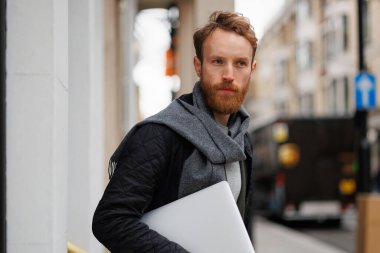 Elinde dizüstü bilgisayarı olan ciddi bir iş adamı binayı terk ediyor.