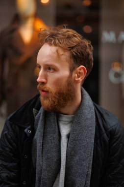 Bir giyim mağazasının arka planında şık sakallı bir adamın portresi