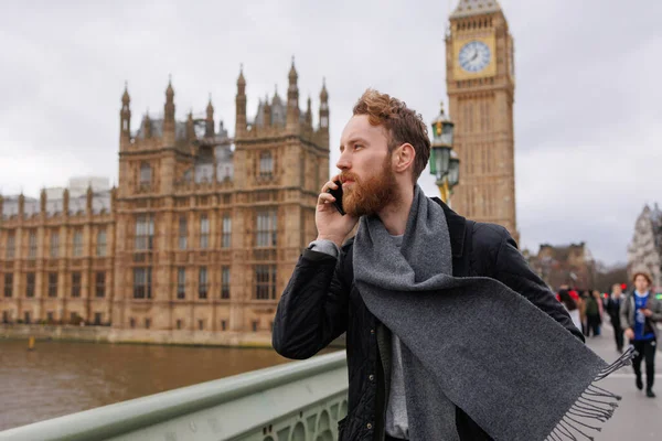 Londra 'nın Big Ben' inin yanında dikilen adam telefonda konuşuyor.