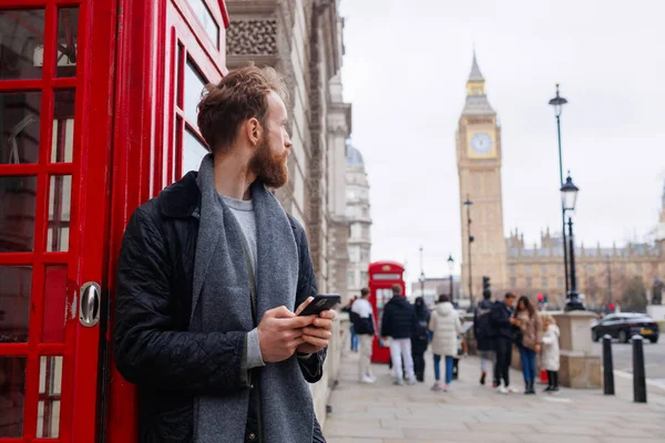 Portret Mężczyzny Odwracającego Wzrok Stojącego Smartfonem Rękach Przy Słynnej Londyńskiej — Zdjęcie stockowe