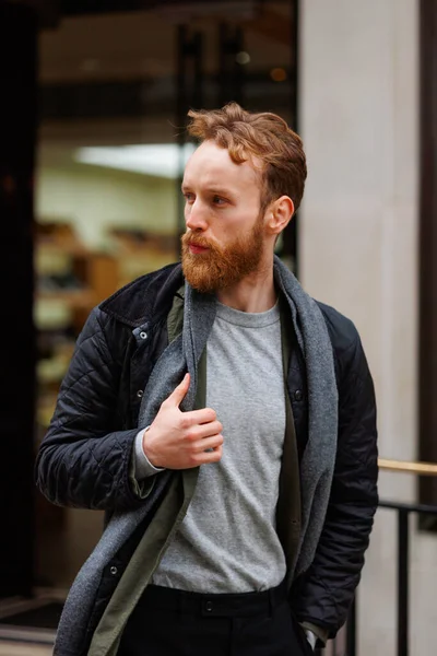 Bearded man in a jacket and scarf walks down the street