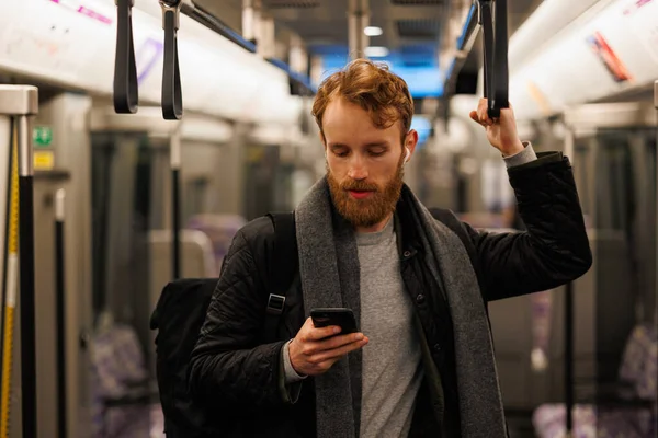 Stylowo Ubrany Brodaty Mężczyzna Stoi Wagonie Metra Słuchawkach Smartfonem Ręku — Zdjęcie stockowe