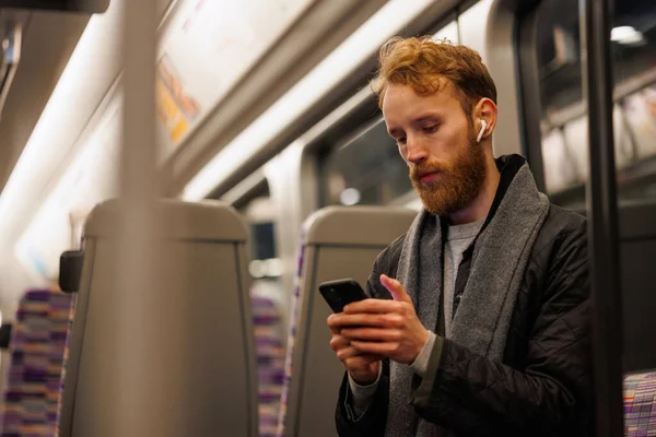 Mężczyzna Pasażer Metra Siedzi Pociągu Słuchając Muzyki Słuchawkach Pomocą Smartfona — Zdjęcie stockowe