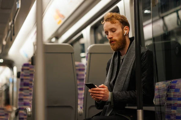 Mężczyzna Pasażer Metra Siedzi Pociągu Słuchając Muzyki Słuchawkach Pomocą Smartfona — Zdjęcie stockowe