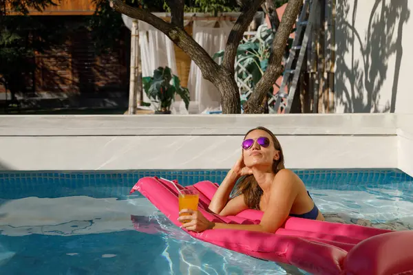 Poolside Chic: Young Lady in Sunglasses on Pink Inflatable Mattress