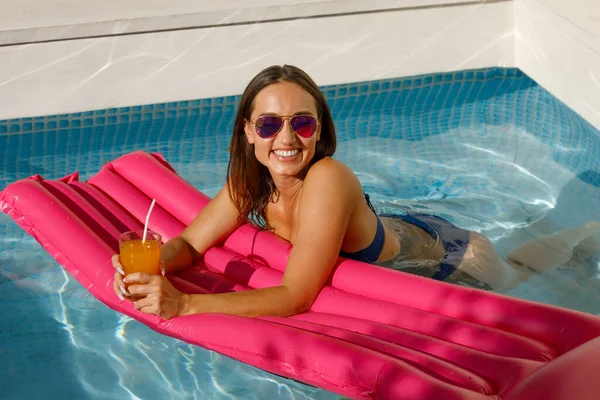 Summer Serenity: Stylish Woman Relaxing on Pink Float in Pool