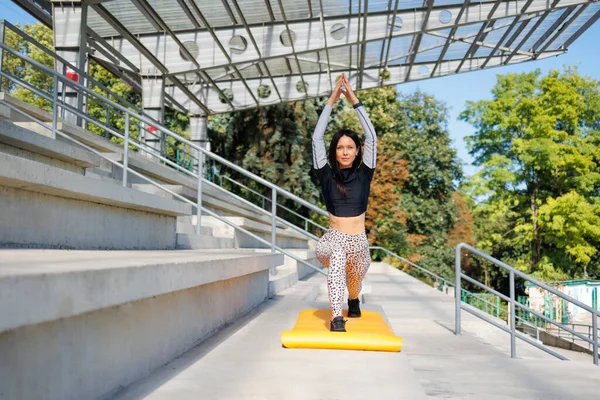 Sportif esmer, stadyumda yoga yapıyor.