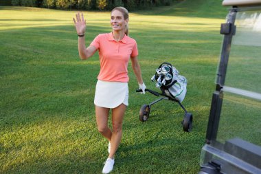 Golf sopalarını taşıyan sarışın golfçü.