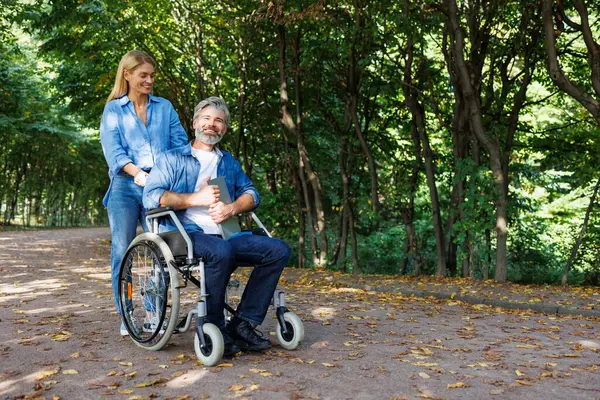 Spacery Integracyjne Kobieta Pomaga Mężczyźnie Wózku Inwalidzkim — Zdjęcie stockowe
