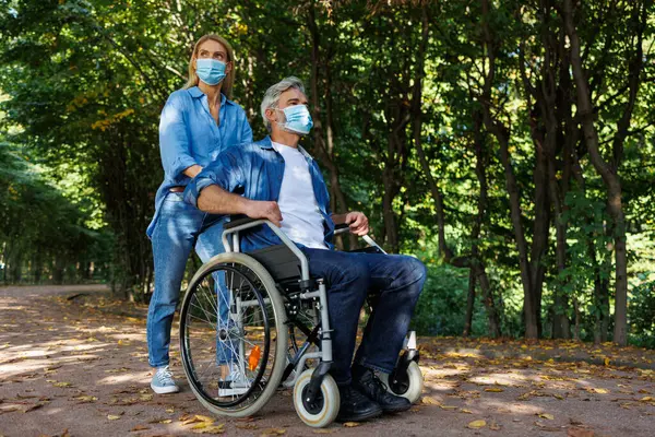 Unity in Adversity: Park Scene with Woman Assisting Man in Wheelchair