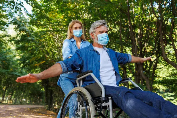 Symbol of Support: Woman and Man in Wheelchair Both Wear Masks in Park