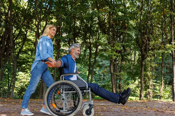 Kobieta Masce Obsługuje Mężczyznę Wózku Inwalidzkim Zewnątrz — Zdjęcie stockowe