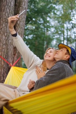 Genç çift Doğa Hamağında Birlikte Rahatlıyor ve Gülümsüyor