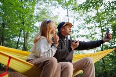 Hamakta sarılıp, görüntülü konuşma yapan çift.