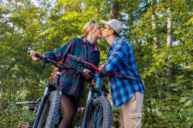 Doğada bisiklet sürerken öpüşen çift.