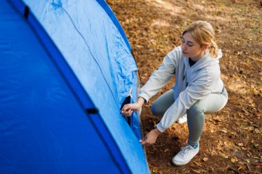Ormanda kamp çadırı açan genç bir kadın.