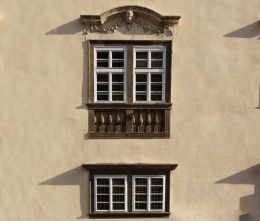 Binanın ön cephesinde 18. yüzyılın iki ahşap antika penceresi açık beton duvarda ahşap kahverengi çerçeveler var.