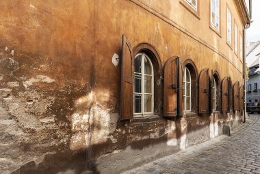 Pencerelerinde açık panjurlar olan eski bir evin kızıl renkli duvarı.