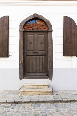 Gökyüzünün yansıması ve camdaki fayanslarla kaplı kahverengi kapılı.