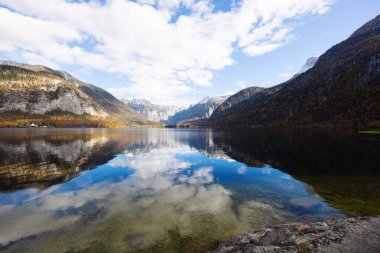 Alp dağları arasında bir dağlık gölde bulutlu gökyüzünün görüntüsü.