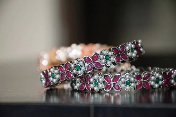 传统印度设计师手镯或女用手镯的照片 白色和红色的钻石装饰在手镯和绿色宝石之间的白色钻石 放在黑桌上 — 图库照片