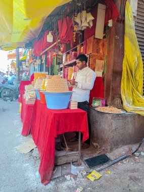 Tulajapur, Hindistan - 28 Ekim 2022; 3-40 yaş arası Hintli adam şekerli süt veya tatlı satarken poğaça fotoğrafı, bir demet şeker mavi renkli konteynır saklıyor.Müşteri için şeker paketliyor.