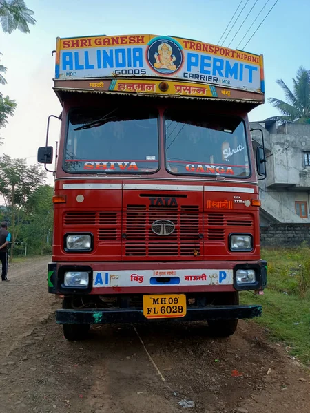 Kolhapur, Hindistan - 1 Kasım 2022; yol kenarına park etmiş kırmızı renkli kamyonun ön görüntüsü, konut binaları, arka planda yeşil ağaçlar. Fotoğraf sabahın erken saatlerinde çekildi. seçici odak.