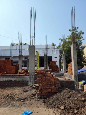 Gulbarga, Hindistan - 27 Kasım 2022; İnşaat halindeki evin stok fotoğrafı, kırmızı tuğlalar, toprak, su tankı, malzemeler, inşaat alanındaki diğer işle ilgili nesneler. Fotoğraf parlak güneş ışığı altında çekildi..